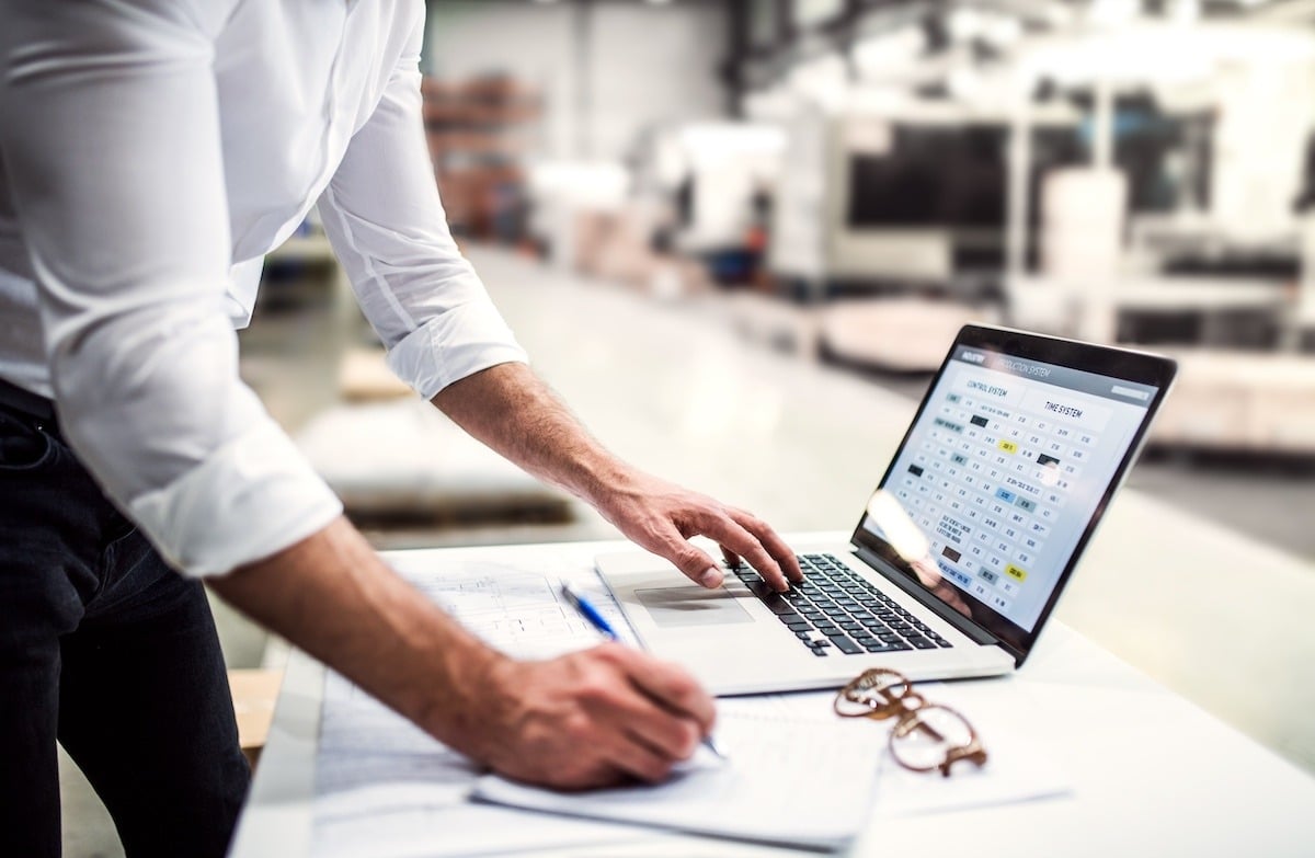 a person at their laptop in a factory learning about the impact of digital transformation in manufacturing