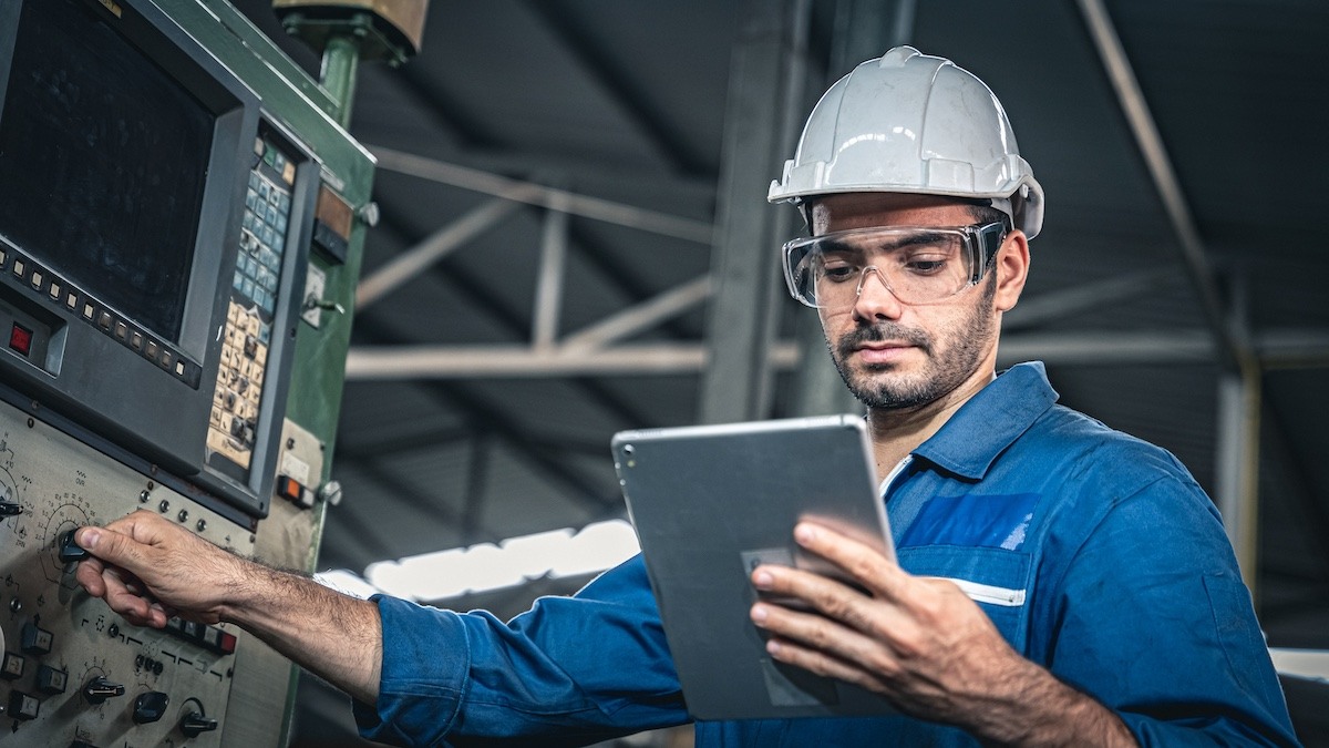 a person working in a manufacturing facility using digital work instructions on their tablet
